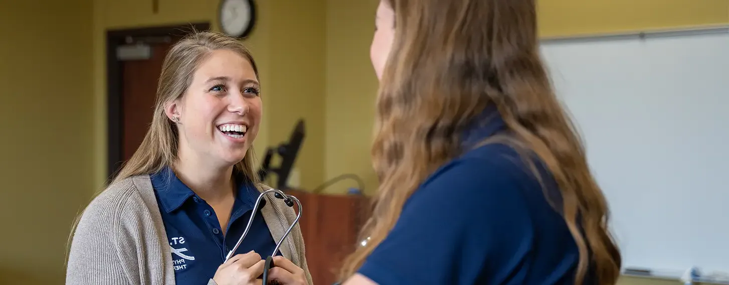 A woman conducting an evaluation on another woman during a physical therapy training.